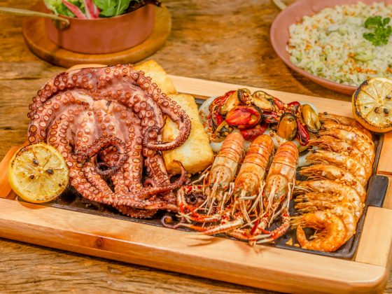 berbagai jenis seafood seperti gurita, udang, kerang di atas nampan kayu di atas meja