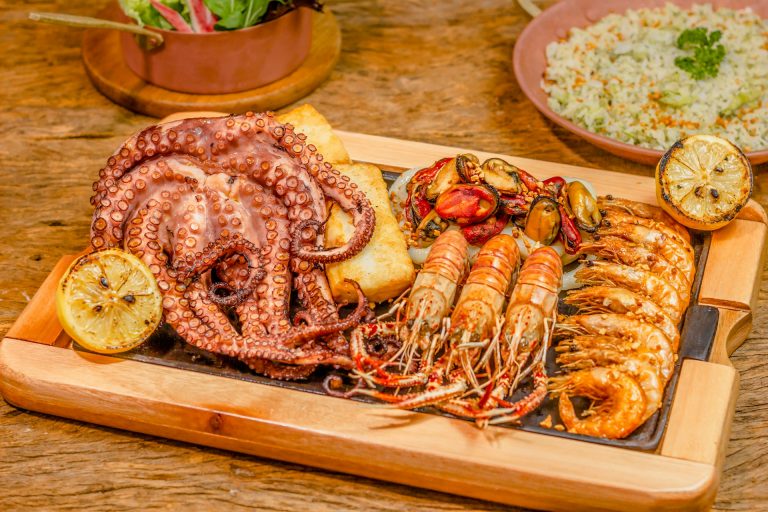 berbagai jenis seafood seperti gurita, udang, kerang di atas nampan kayu di atas meja