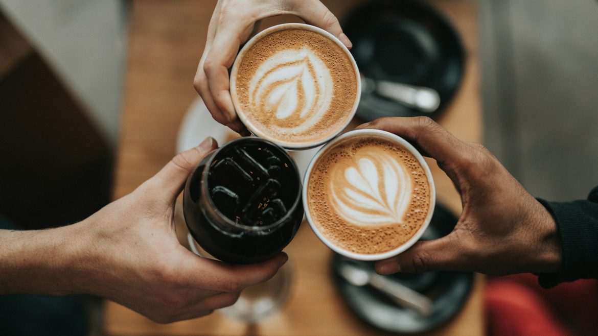 tiga tangan memegang tiga cangkir kopi