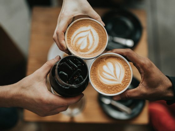 tiga tangan memegang tiga cangkir kopi