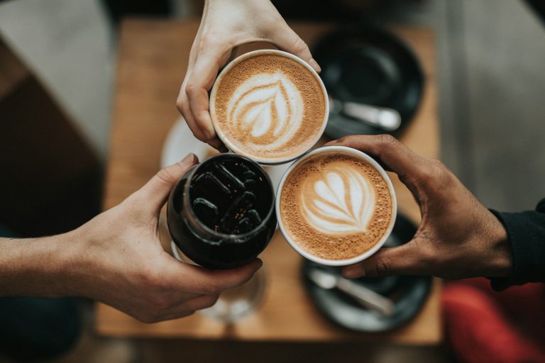 tiga tangan memegang tiga cangkir kopi