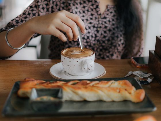 perempuan sedang minum kopi dan roti di cafe