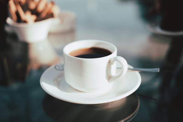 secangkir kopi hitam di atas meja kaca